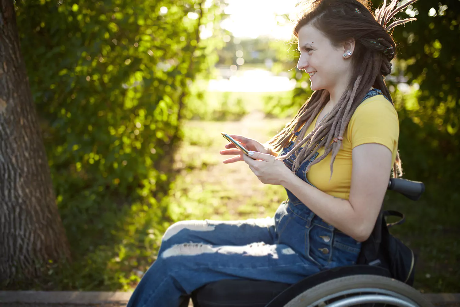 A young woman with a physical disability is using her phone outdoors